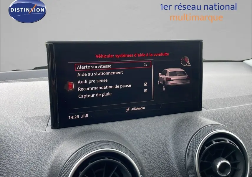 Écran central affichant les aides à la conduite dans l'habitacle d'un Audi Q2 noir mito metal, vue de face.