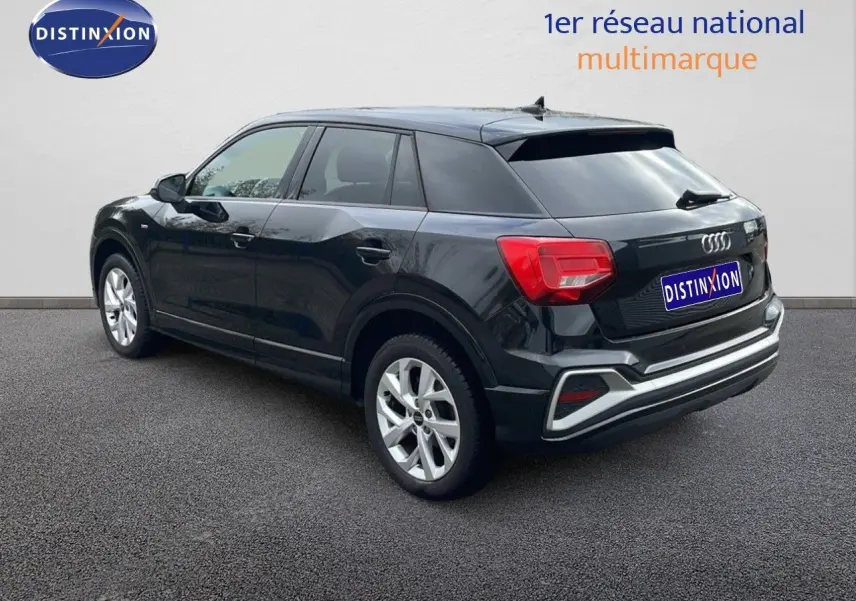 Audi Q2 35 TFSI S-Line noir mito metal, vue 3/4 arrière droit, feux arrière rouges et jantes argentées visibles.