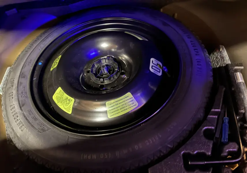 Vue rapprochée de la roue de secours noire et des outils dans le coffre du Peugeot 2008 GT Line noir 2020.