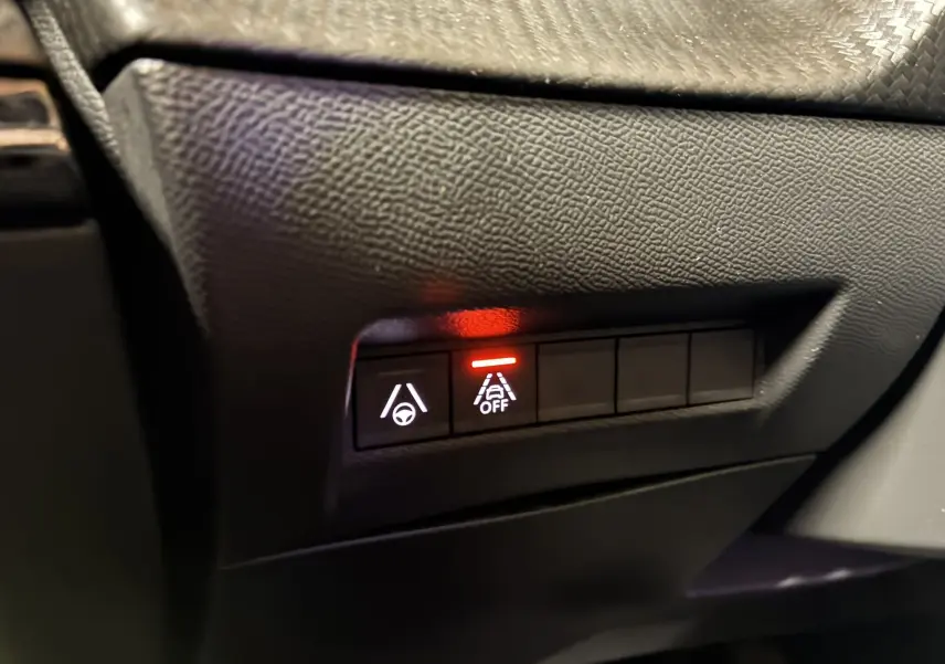 Gros plan sur les boutons de contrôle d'aide à la conduite du tableau de bord d'un Peugeot 2008 noir, version GT Line.