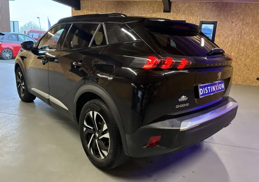 Vue 3/4 arrière droite d'un Peugeot 2008 noir avec feux arrière LED et jantes bi-ton en intérieur garage.