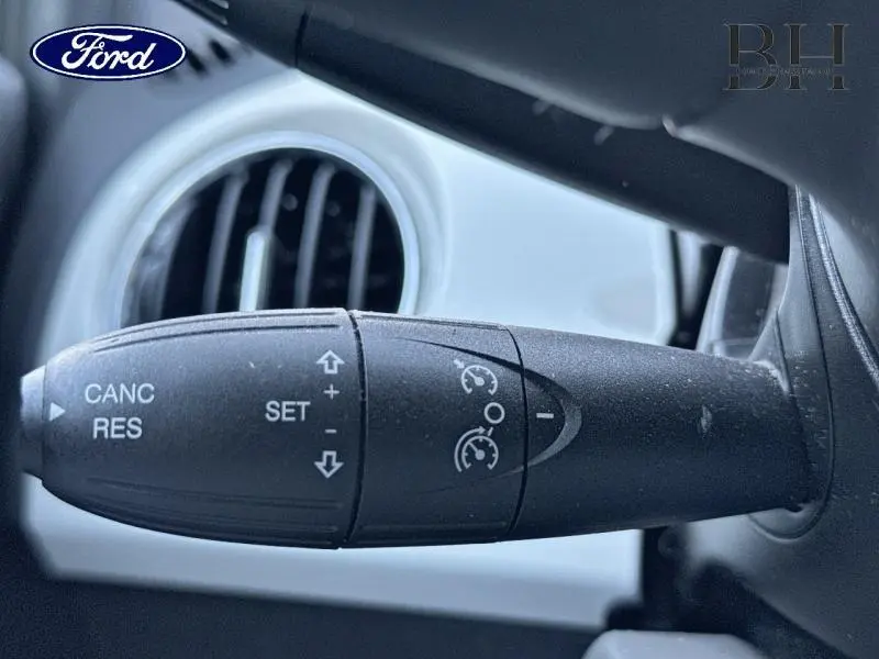 Gros plan sur la commande de régulateur de vitesse noire, avec aérateur rond blanc en arrière-plan intérieur FIAT 500 blanc.