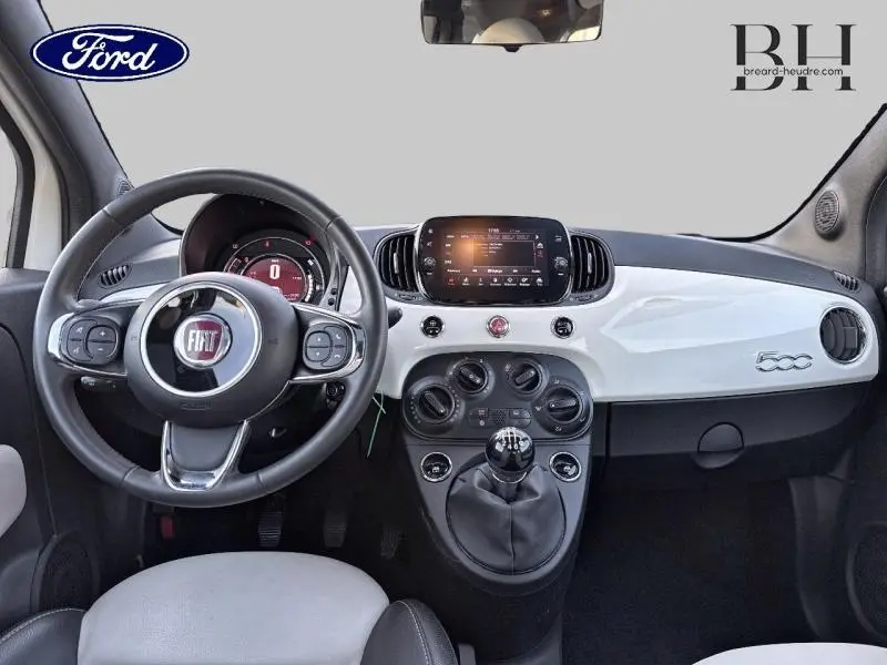Vue intérieure avant du tableau de bord blanc Bossa Nova de la Fiat 500 avec volant cuir multifonction et écran tactile central.