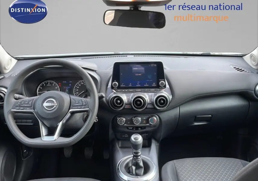 Vue intérieure frontale du tableau de bord du Nissan Juke noir perle 2023 avec volant multifonction et écran tactile central.