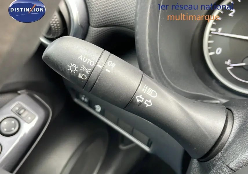 Gros plan sur la commande des feux et clignotants dans l’habitacle noir perle métal du Nissan Juke 2023.