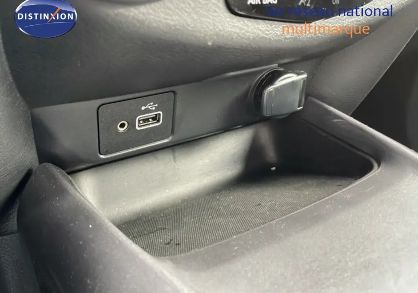 Gros plan sur la prise USB et l’allume-cigare dans l’espace de rangement intérieur noir du Nissan Juke 2023.