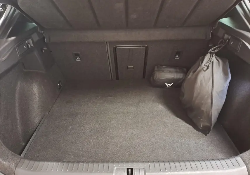 Coffre ouvert vu de l'arrière du CUPRA Formentor noir Minuit 2023 avec sac et trousse de rangement à droite.