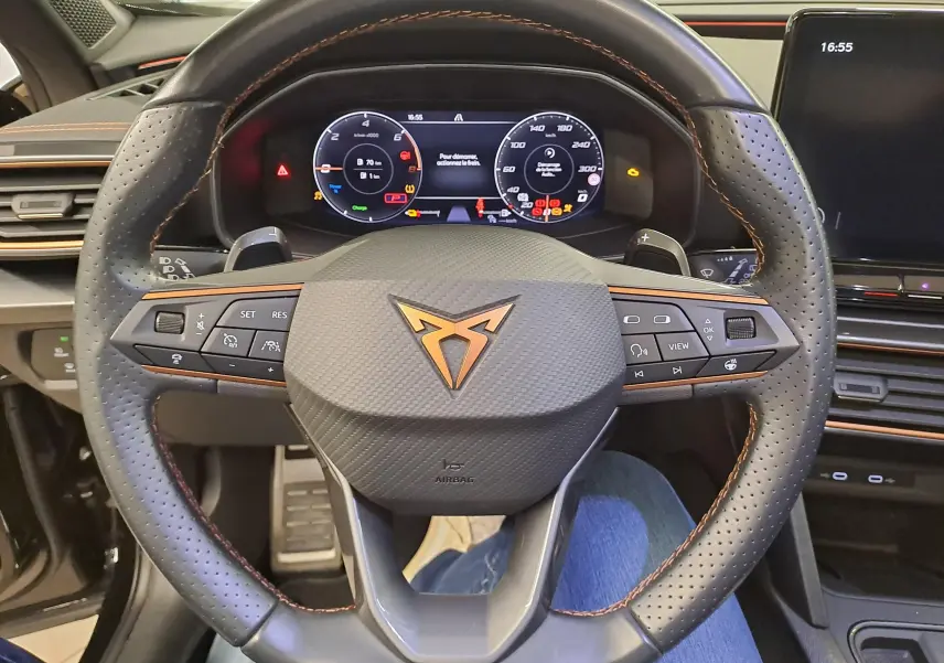 Vue rapprochée du volant perforé noir avec surpiqûres cuivre et tableau de bord numérique du CUPRA Formentor 2023.