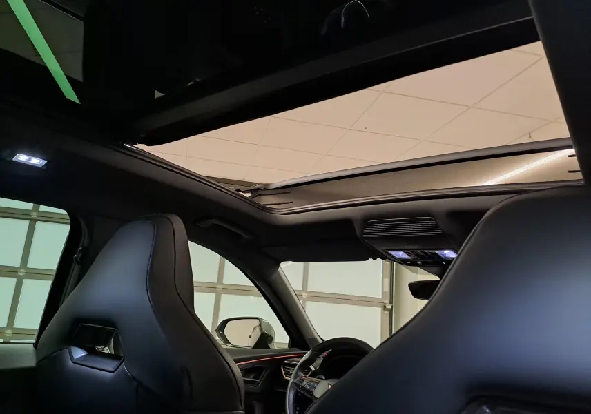 Vue intérieure du toit ouvrant panoramique du CUPRA Formentor noir minuit, avec sièges baquets en cuir et éclairage ambiant.