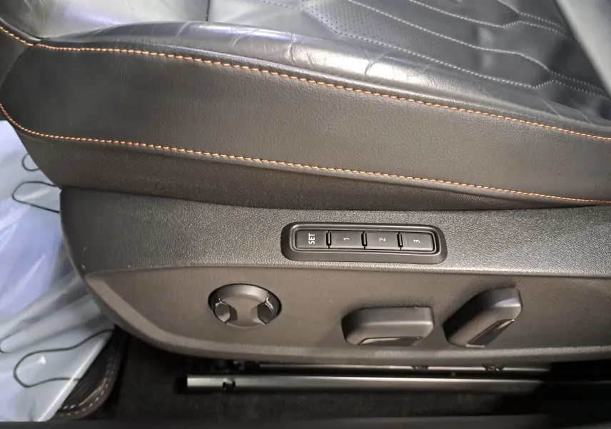 Détail du siège baquet en cuir noir Asphalte avec surpiqûres copper et commandes électriques de réglage.