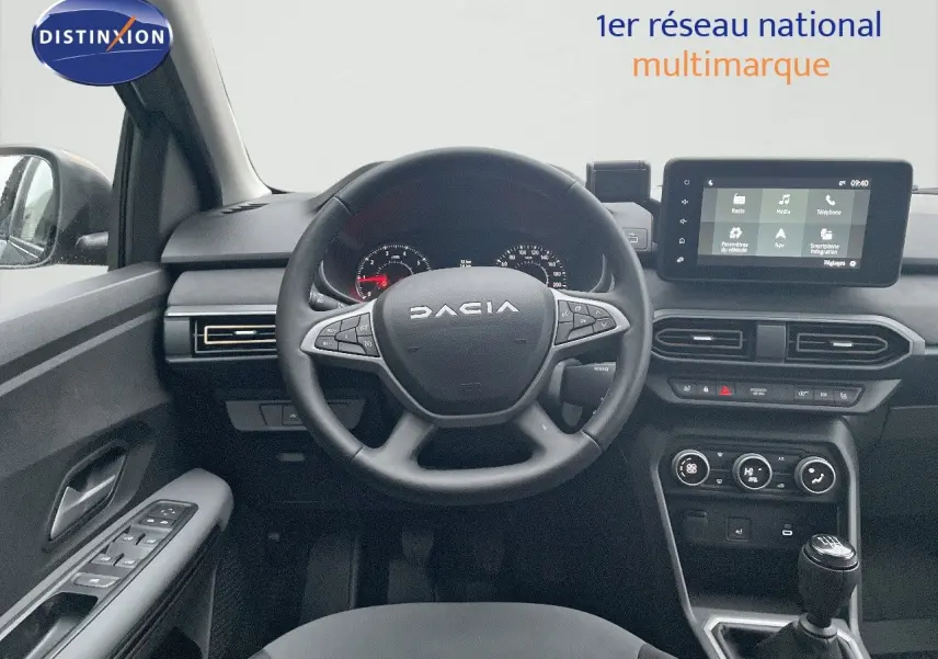 Vue intérieure centrée sur le volant DACIA et la console centrale avec écran tactile, ambiance noire moderne.