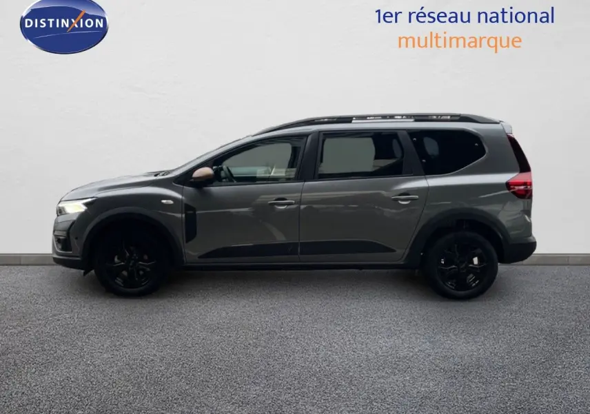 Profil droit du Dacia Jogger gris schiste métal 2026 avec jantes noires et barres de toit visibles.