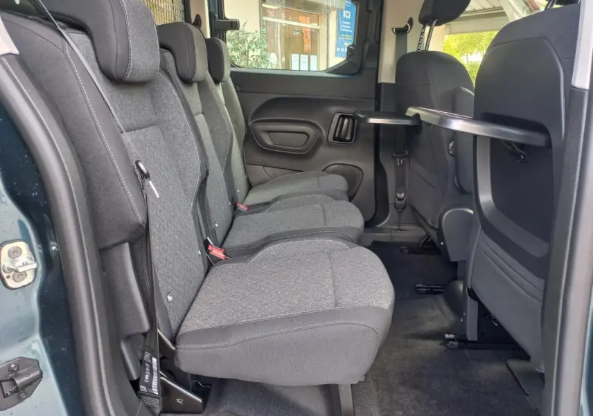 Vue intérieure côté gauche des sièges arrière gris du Opel Combo Life Elegance M 2025, avec tablette rabattable sur le dossier avant.