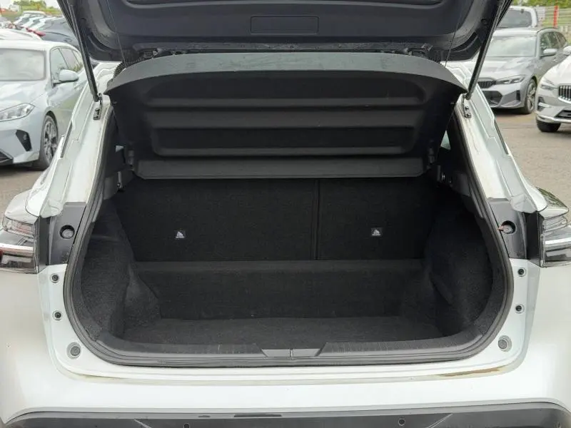 Coffre ouvert vu de l'arrière du Nissan Qashqai blanc nacré, montrant l'espace de chargement vide.