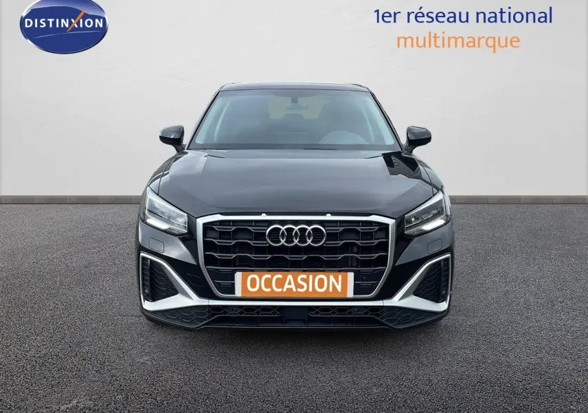 Vue frontale d'un Audi Q2 35 TFSI S-Line noir mito metal avec calandre hexagonale et phares LED allumés.