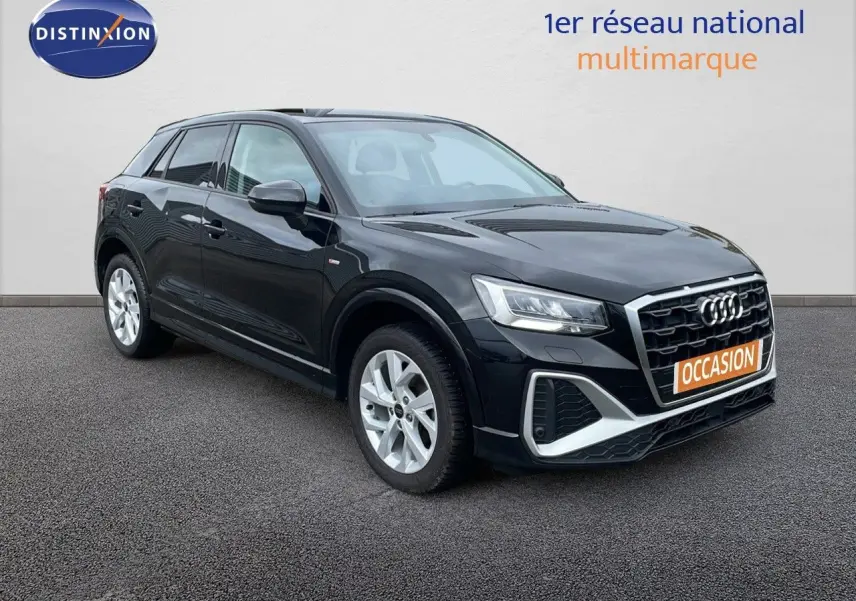 Audi Q2 noir mito metal en 3/4 avant droit, avec calandre S-Line et jantes argentées visibles sur sol gris.