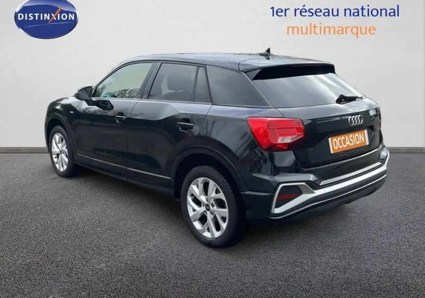 Audi Q2 noir mito metal vue 3/4 arrière côté gauche, avec feux arrière rouges et jantes argentées.