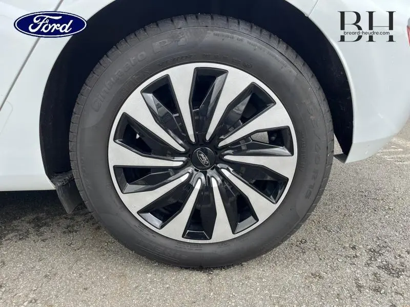 Gros plan sur la roue avant droite d'une Ford Fiesta blanche avec jante alu bicolore au design moderne.