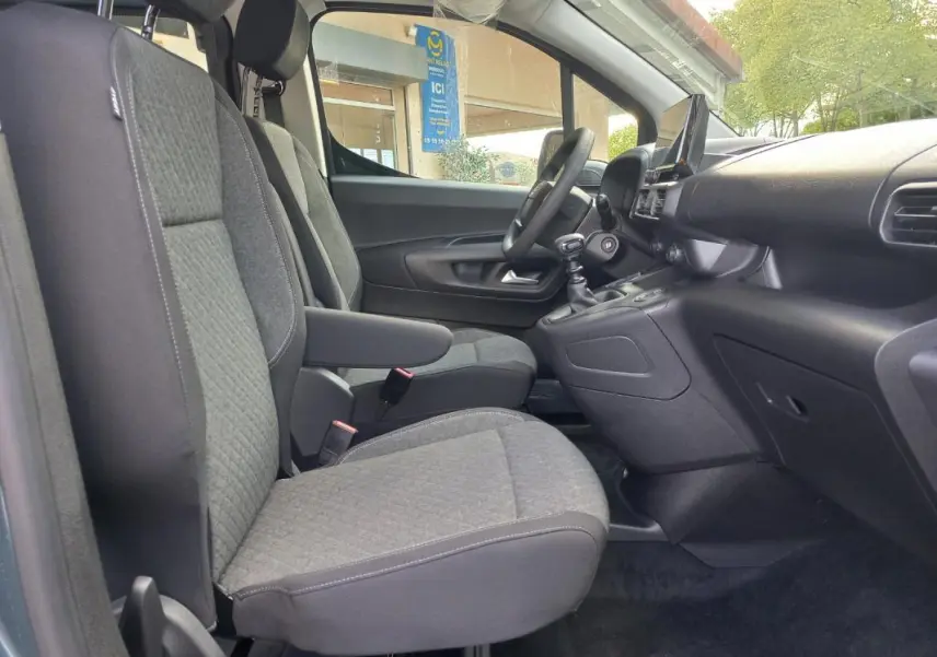 Vue intérieure côté conducteur de l’Opel Combo Life M 2025, sièges gris avec accoudoir et tableau de bord noir.