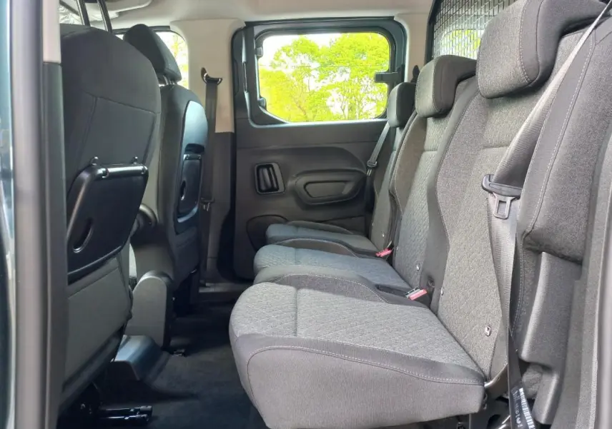 Vue latérale intérieure sur la banquette arrière grise de l’Opel Combo Life M 2025, avec tablettes pliantes au dos des sièges avant.