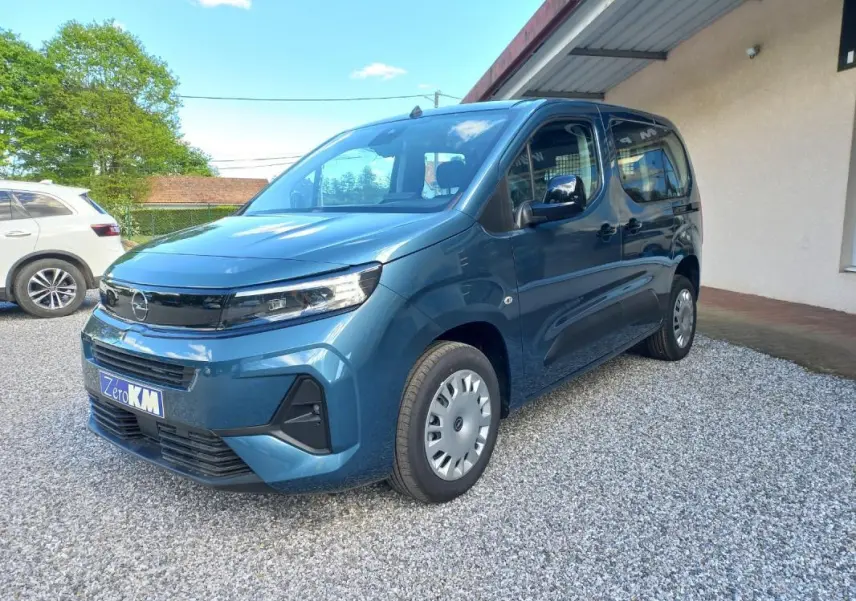 Opel Combo Life bleu en vue 3/4 avant droit, avec calandre noire et jantes acier argentées sur gravier.