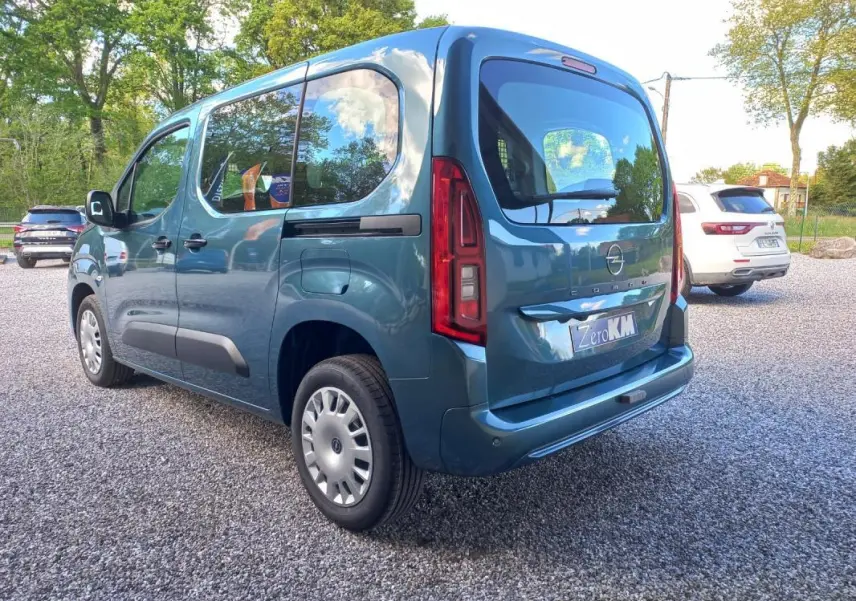 Opel Combo Life bleu en vue 3/4 arrière droit, avec vitres latérales teintées et feux arrière verticaux rouges.