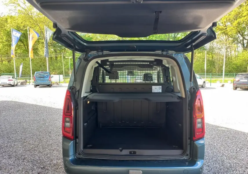 Vue arrière ouverte du fourgon Opel Combo Life M bleu 2025, montrant l'espace de chargement avec séparation grillagée.