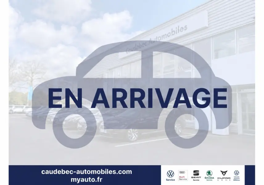 Vue 3/4 avant d’un Volkswagen Touran gris stationné devant un bâtiment de concession automobile.