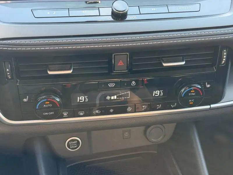 Vue rapprochée de la console centrale du Nissan Qashqai 2025 en noir Kuro, affichant la climatisation bi-zone digitale.
