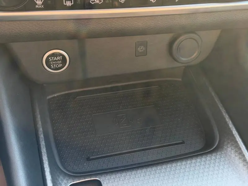 Gros plan sur la console centrale noire du Nissan Qashqai 2025, avec bouton Start/Stop et zone de recharge sans fil.