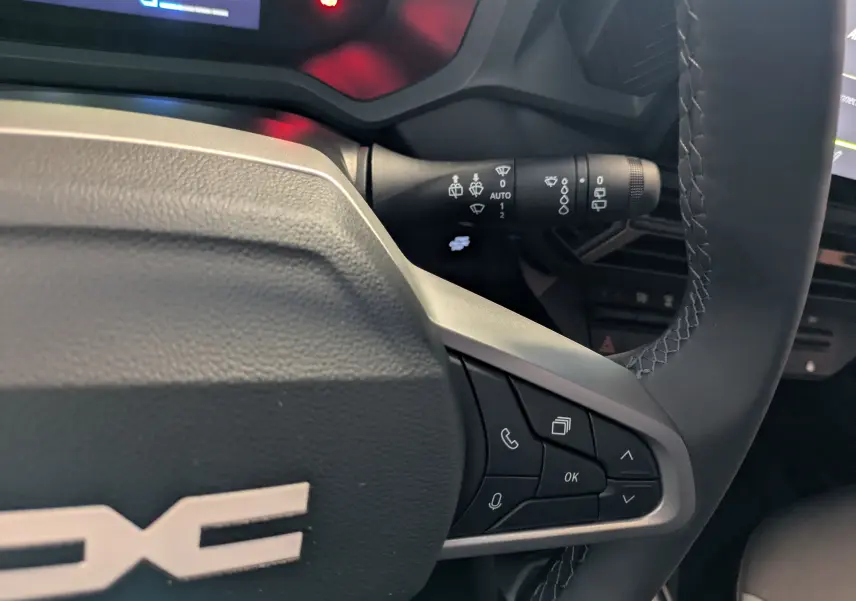 Gros plan sur le volant du Dacia Duster 1.6 Hybrid 140 Extreme 2025, avec commandes intégrées et surpiqûres visibles.