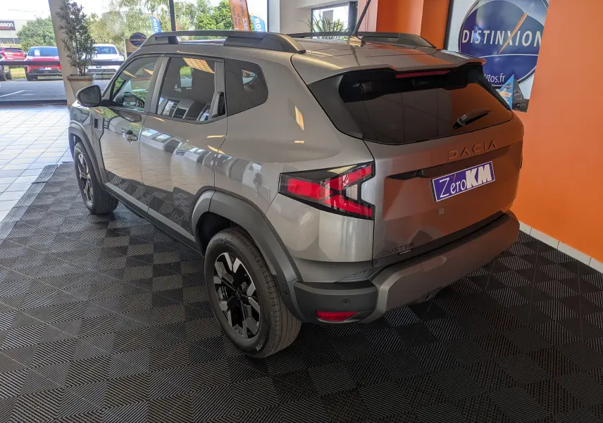 Vue 3/4 arrière droite du Dacia Duster 1.6 Hybrid 140 Extreme gris schiste avec jantes bicolores et vitres teintées.