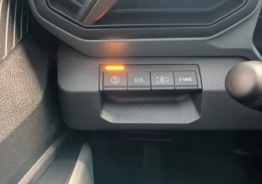 Boutons de commande du tableau de bord du Dacia Duster 1.6 Hybrid 140 Extreme 2025, vue rapprochée avec témoin orange allumé.