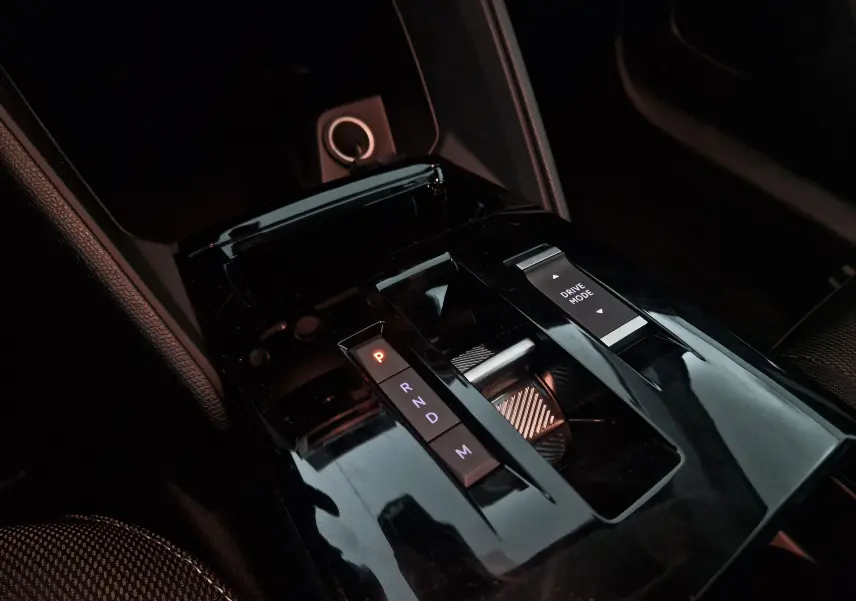 Gros plan sur la console centrale noire brillante de la Citroën C4 1.2 HYBRID 136 e-DSC6 PLUS avec sélecteur de boîte auto et bouton Drive Mode.