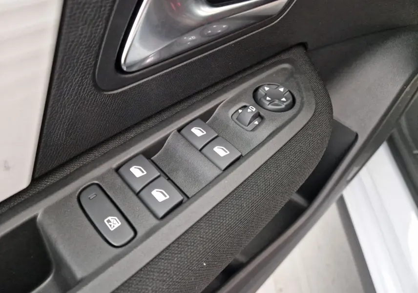 Gros plan sur les commandes de lève-vitres et rétroviseurs côté conducteur d'une Citroën C4 blanche 2025.