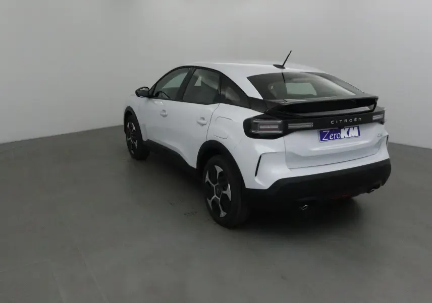 Vue 3/4 arrière droite d'une Citroën C4 blanc Okenite avec toit noir et jantes stylisées dans un studio.