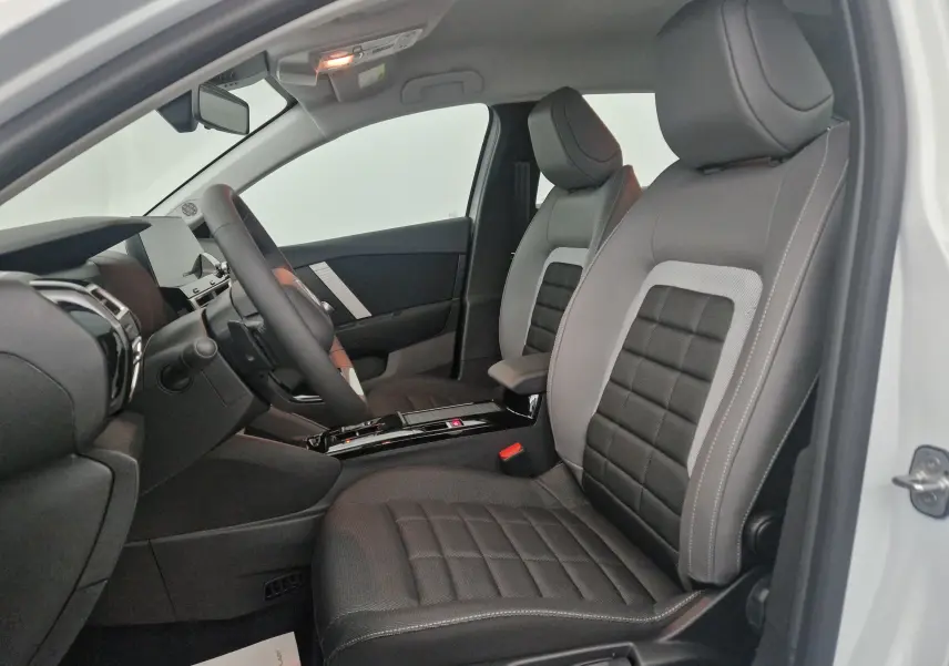 Vue intérieure côté conducteur de la Citroën C4 1.2 Hybrid 136 e-DSC6 Plus 2025 avec sièges tissu noir et gris.