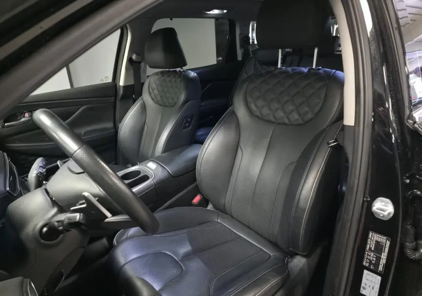 Vue intérieure côté conducteur du Hyundai Santa Fé 2023 noir, sièges cuir noir matelassé et volant cuir perforé.
