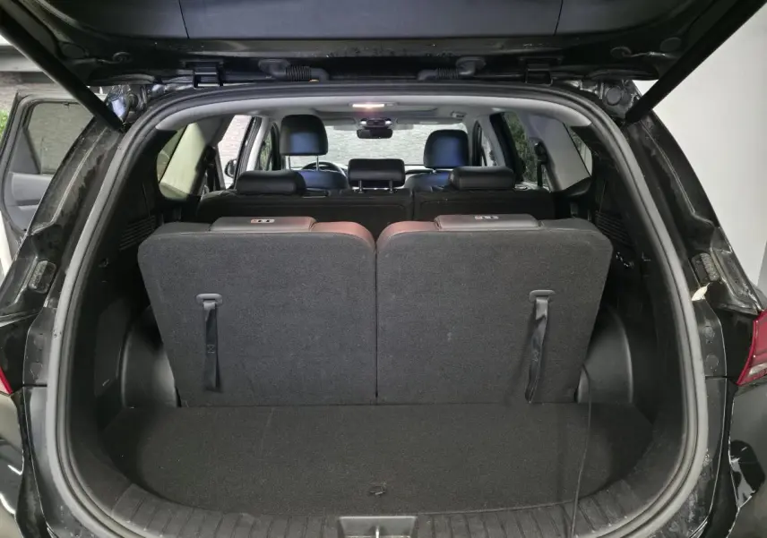 Vue arrière du coffre ouvert du Hyundai Santa Fé noir 2023, montrant la troisième rangée de sièges relevée.