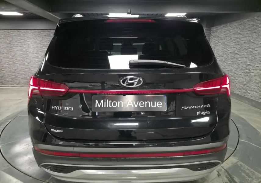 Vue arrière d'un Hyundai Santa Fé noir hybride rechargeable avec feux LED et logo distinctif dans un garage.