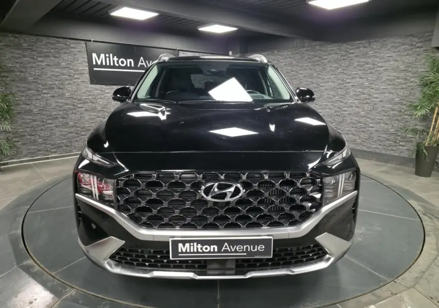 Vue frontale d'un Hyundai Santa Fé noir avec calandre hexagonale chromée et éclairage LED dans un showroom.