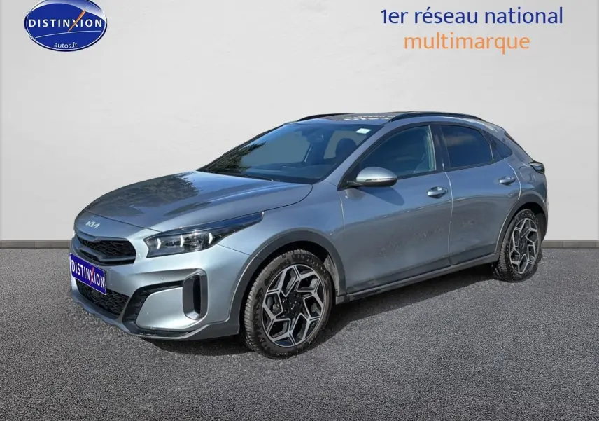 KIA Xceed gris en 3/4 avant droit, avec jantes alu au design hexagonal et calandre chromée visible.