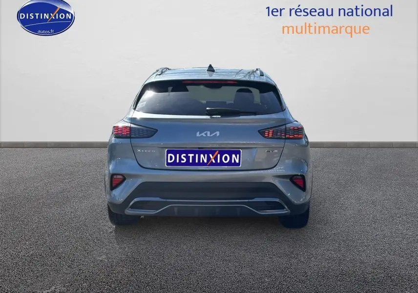 Vue arrière d'un KIA Xceed gris 2024 avec feux arrière LED et becquet intégré sur un sol bitumé.