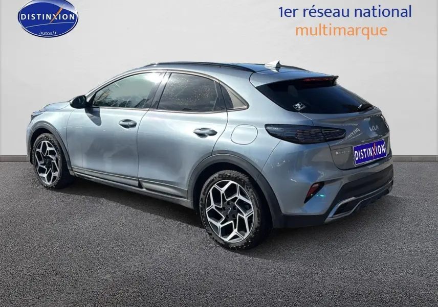 Vue 3/4 arrière droite d'un KIA Xceed gris avec jantes alu et vitres arrière surteintées sur fond neutre.