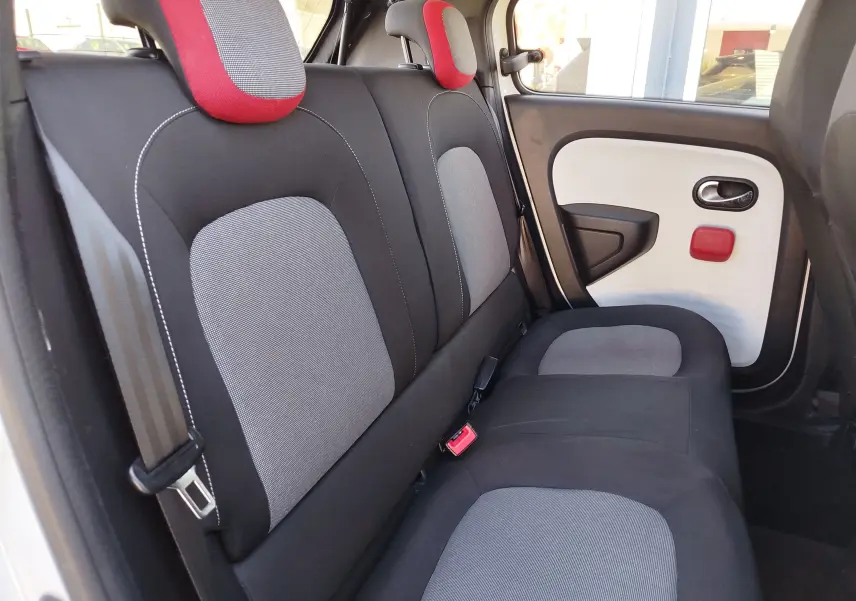 Vue intérieure arrière côté droit de la Renault Twingo blanc cristal, sièges noirs et gris avec appuie-têtes rouges.