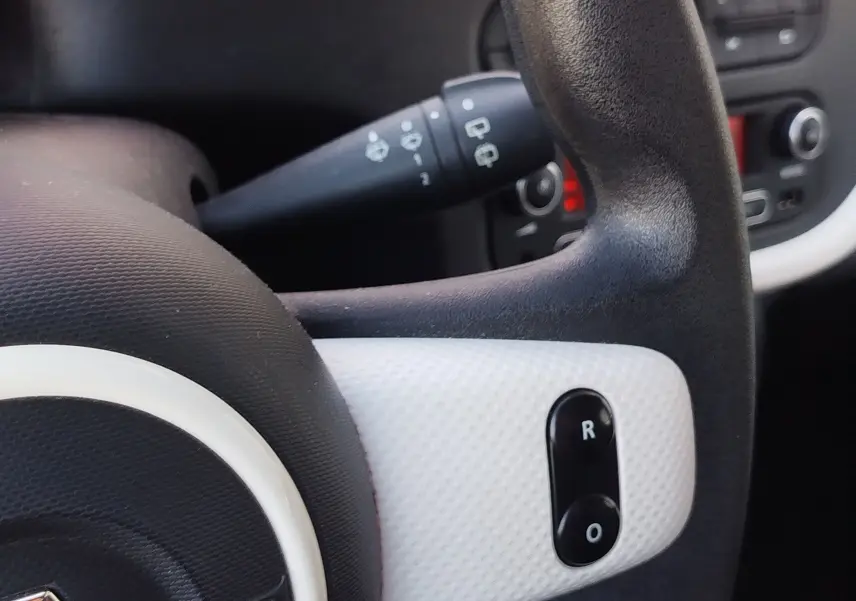 Gros plan sur le volant noir et blanc texturé de la Renault Twingo 2016, avec commandes intégrées visibles.