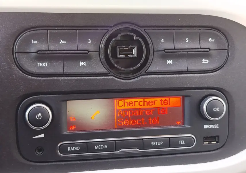 Vue rapprochée de la console centrale de la Renault Twingo blanche 2016, affichant l'écran radio avec menu téléphone.