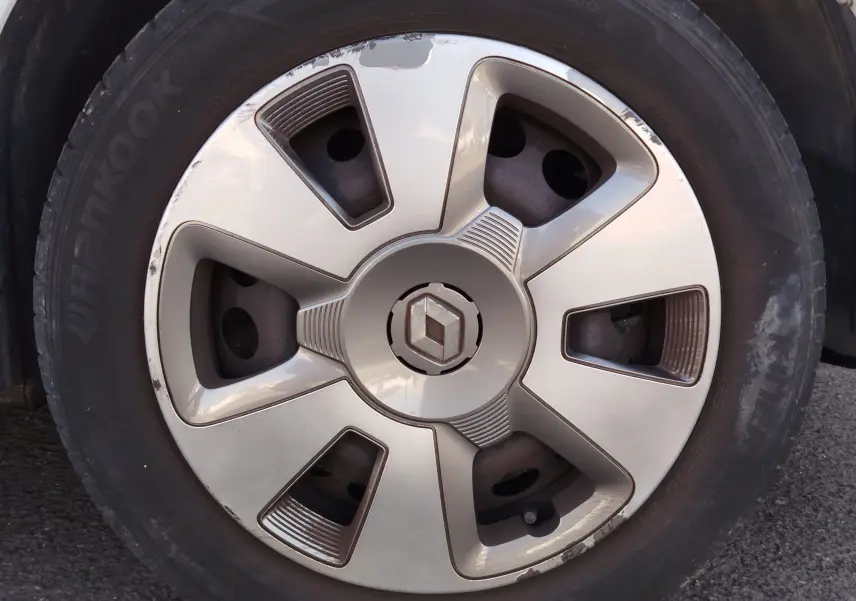 Gros plan sur la roue avant droite d'une Renault Twingo blanc cristal de 2016 avec jante en alliage et logo Renault central.