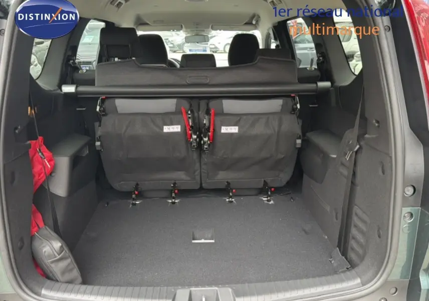 Vue arrière du coffre ouvert d'un Dacia Jogger vert cèdre métal, montrant les sièges rabattus et l'espace de chargement.