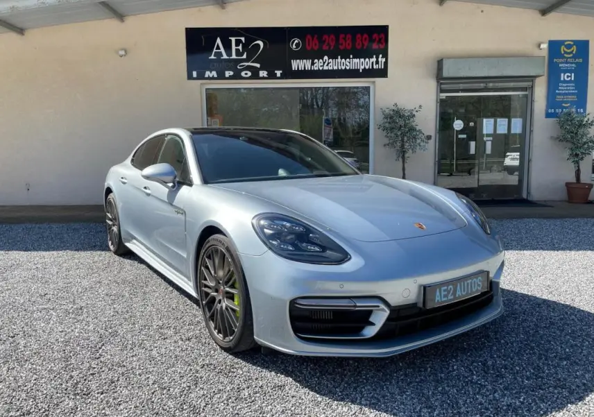 Porsche Panamera 4 V6 Hybrid gris vue 3/4 avant droit, jantes noires et étriers de frein verts visibles.